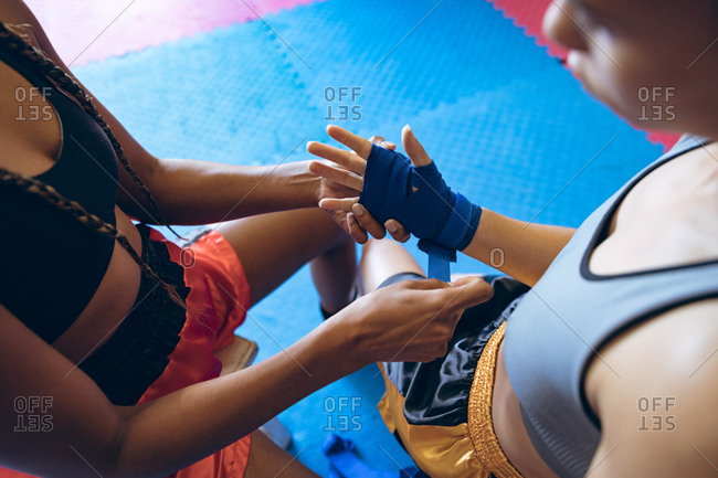Female trainer putting hand wrap to female boxer in boxing club