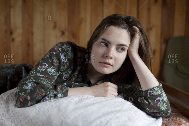 Young woman lying on cushion on bed