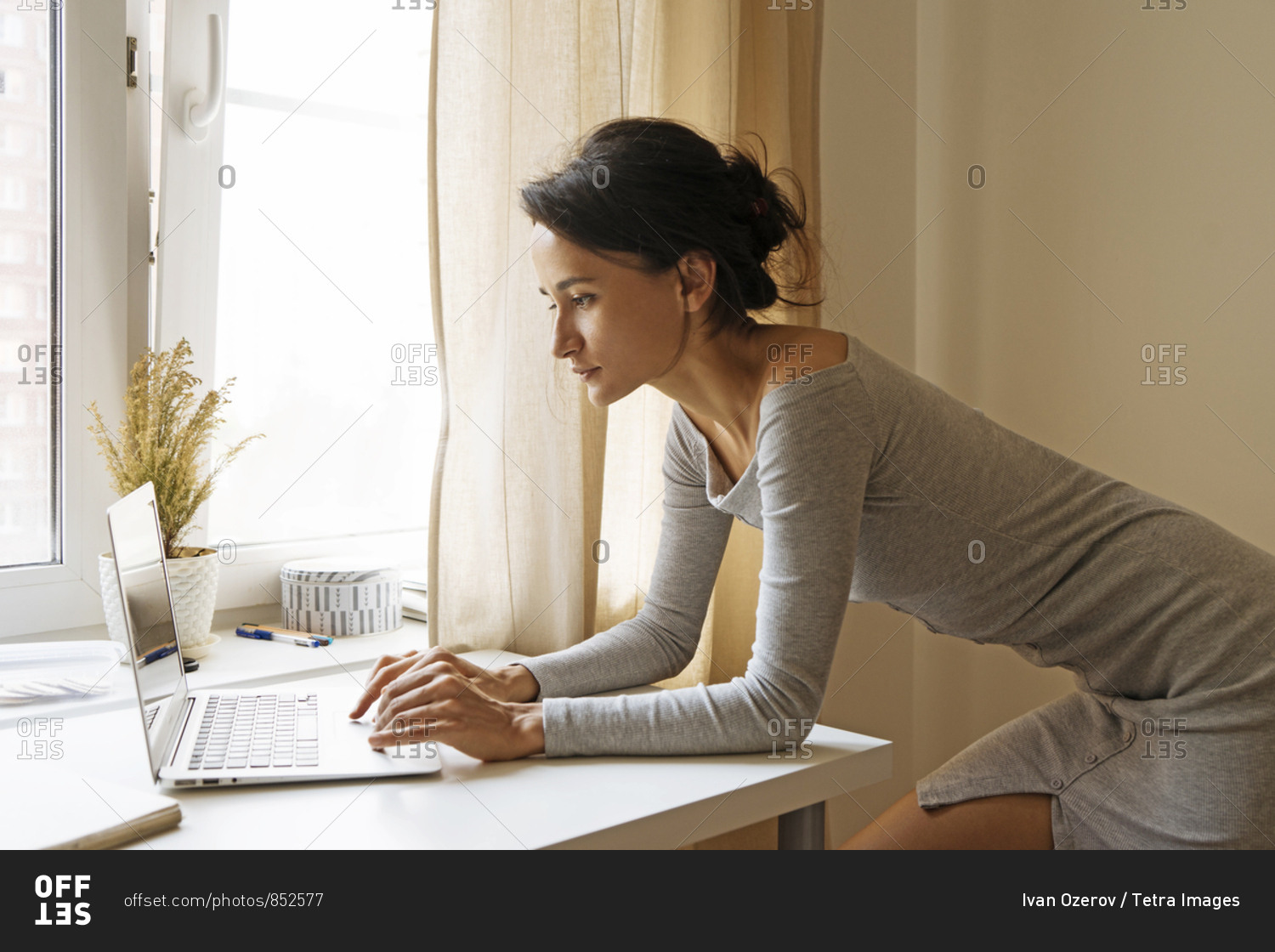 Woman leaning on table using laptop stock photo OFFSET