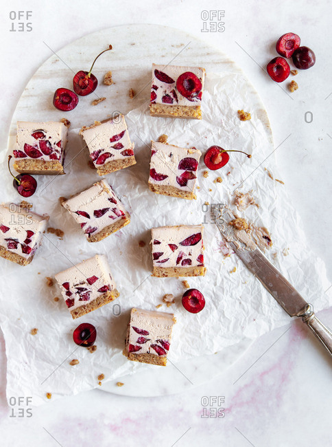 white chocolate and cherry raw vegan bars on marble cutting board with vintage knife