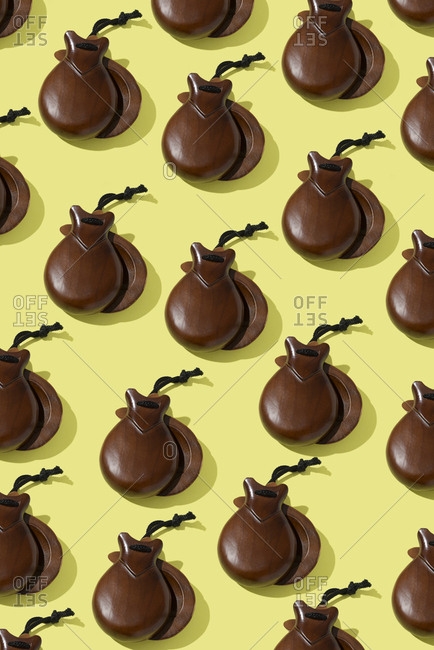 Overhead view of some pairs of wooden castanets on a yellow background
