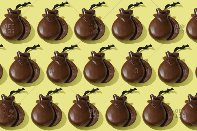 High angle view of some pairs of wooden castanets on a yellow background