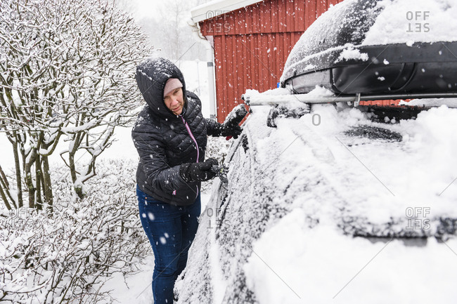 Woman clearing snow from car
