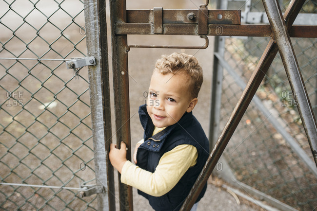 Boy stands behind a fence