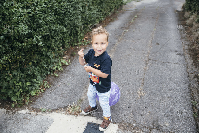 Boy plays with happy birthday balloon on pathway
