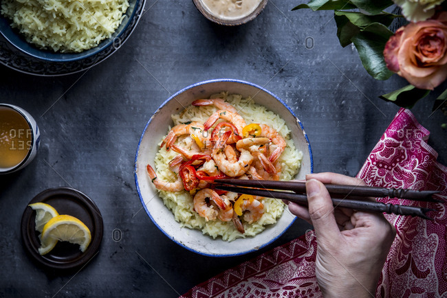 Hand holding chopsticks while eating basmati Indonesian shrimp rice