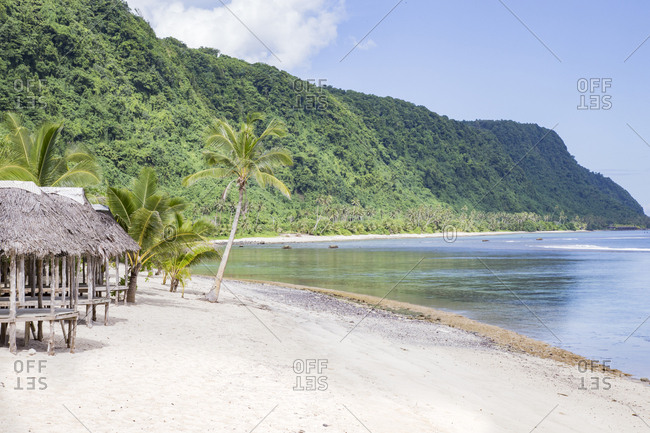 Beach huts on tropical exotic sandy beach of Samoa, under blue sky