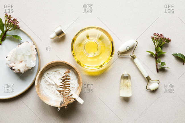 Flatlay of beauty products including oil, facial roller, and crystal