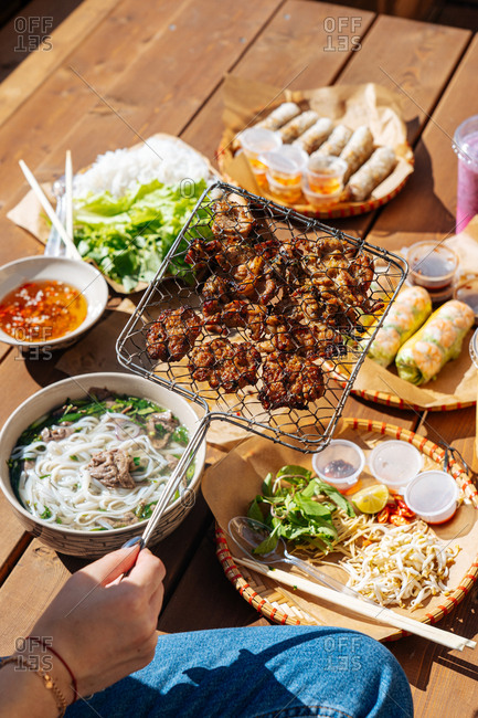 Woman eating Asian cuisine on outdoor table