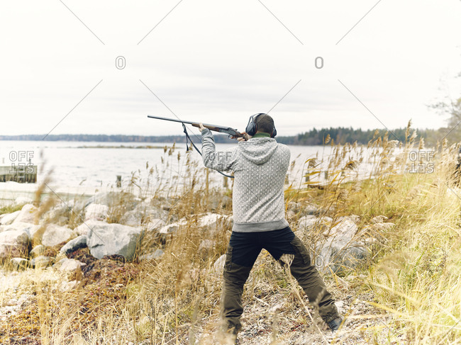 Man shooting rifle by sea