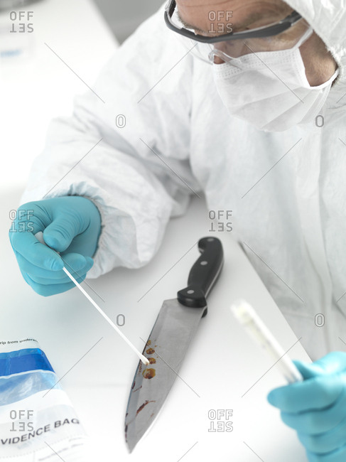 Forensic scientist taking DNA evidence from a blood smeared knife