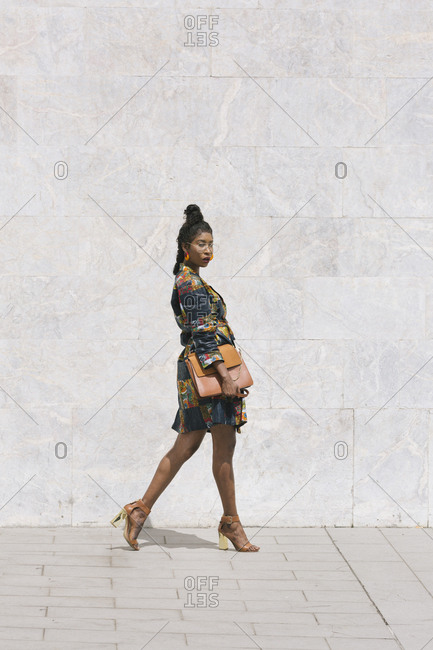 Portrait of chic woman wearing patterned dress walking outdoors
