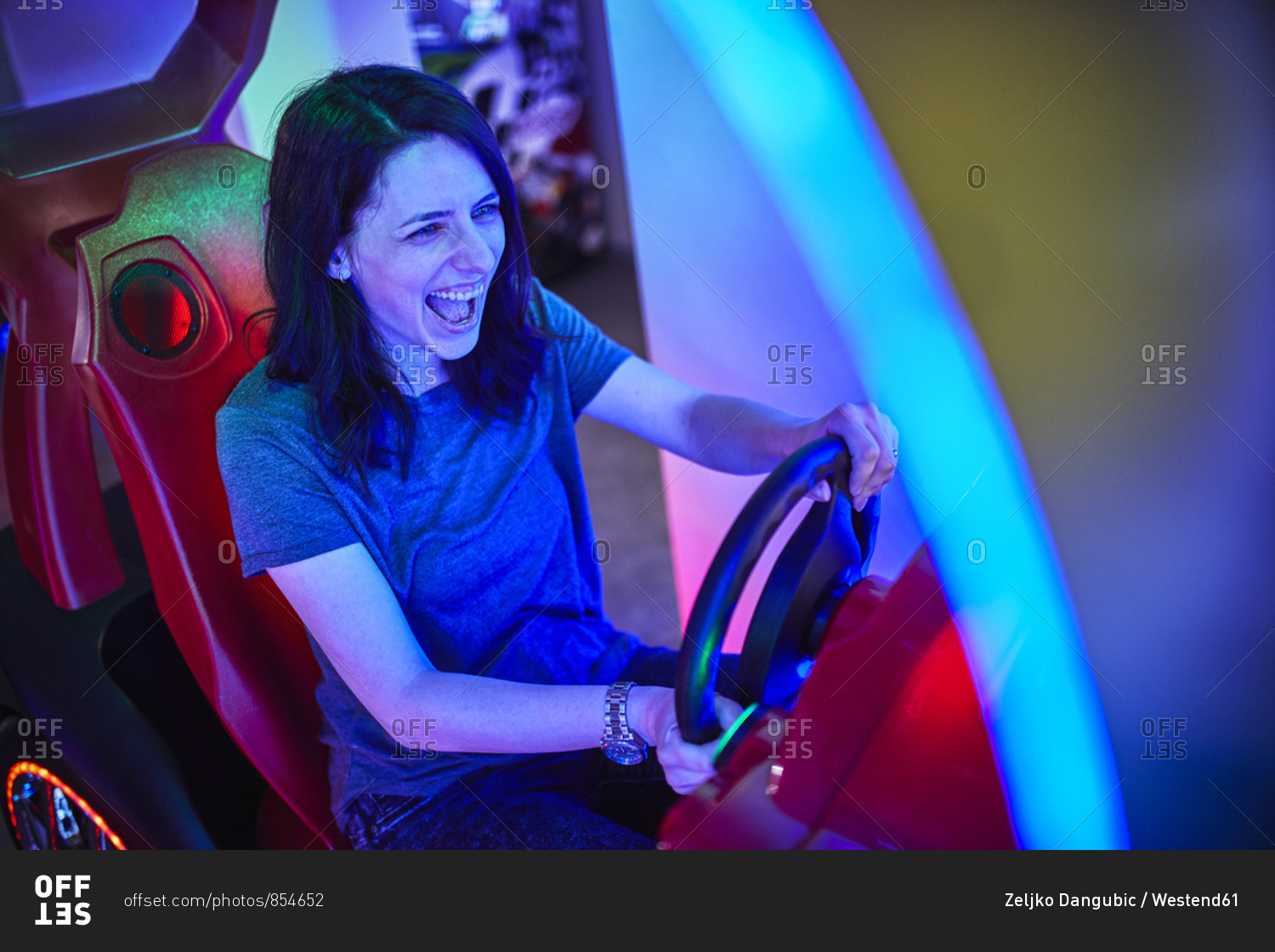 Excited woman playing and having fun with a driving simulator in an amusement arcade