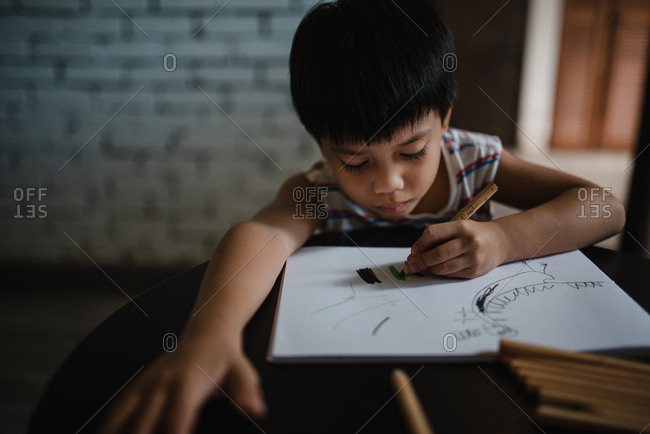 Asian boy drawing with color pencils