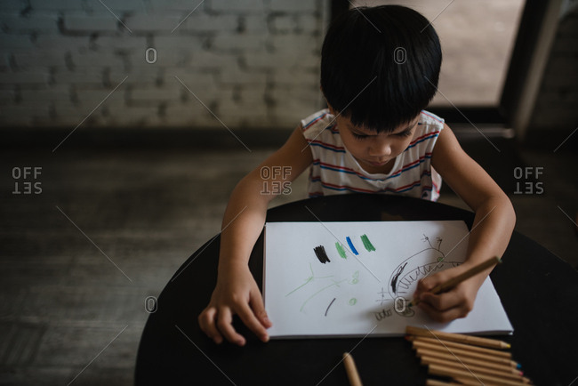 Asian boy drawing with color pencils