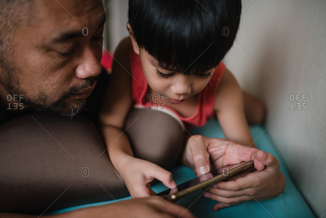 Boy with father playing games on smartphone