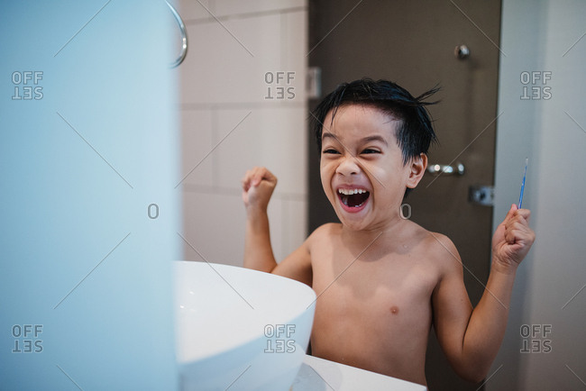 Asian boy combing hair in front of mirror