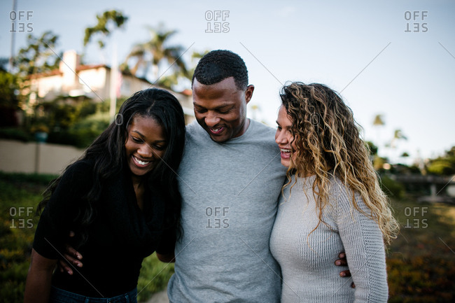 Blended family smiling and hugging on beach at sunset