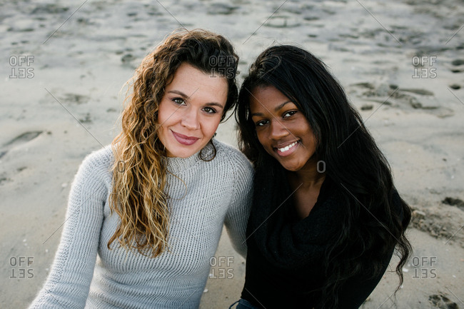 Step mom and step daughter smiling at camera on beach at sunset