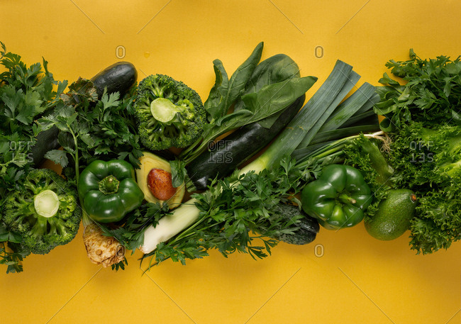 Fresh green vegetables on yellow background