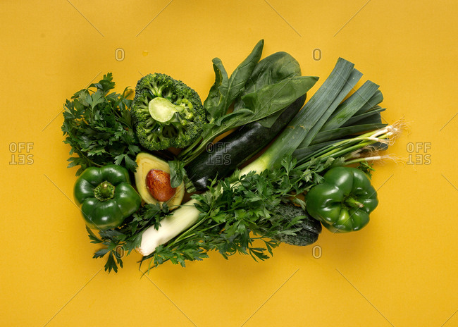 Fresh green vegetables on yellow background
