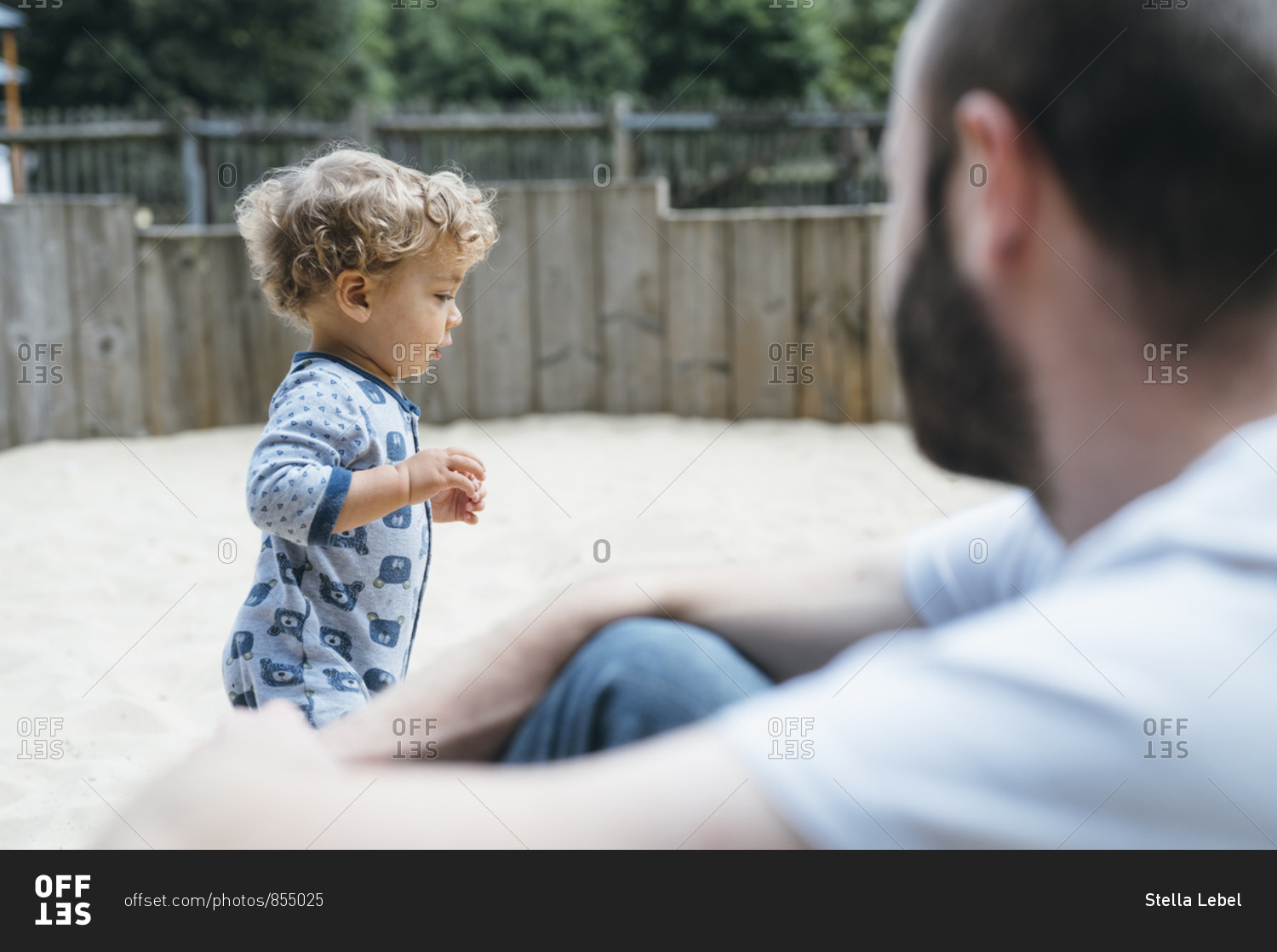 Father looks at his son playing in sandpit