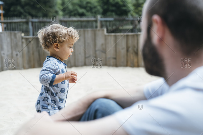 Father looks at his son playing in sandpit