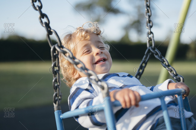 Young boy swinging on playground.