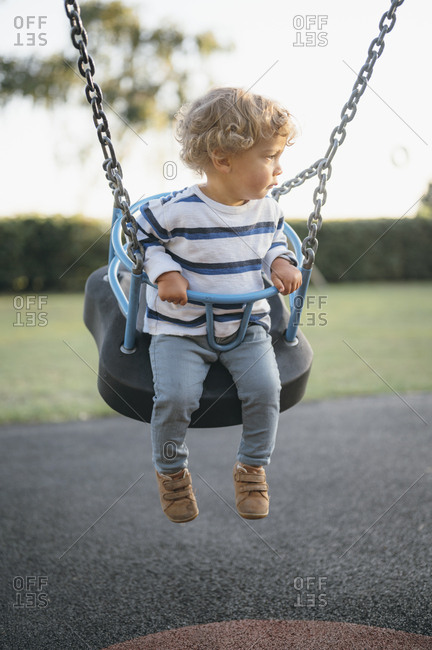 Young boy swinging on playground.