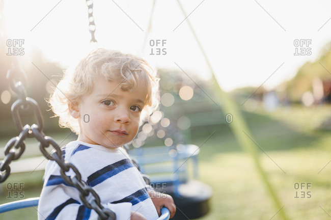 Young boy swinging on playground.