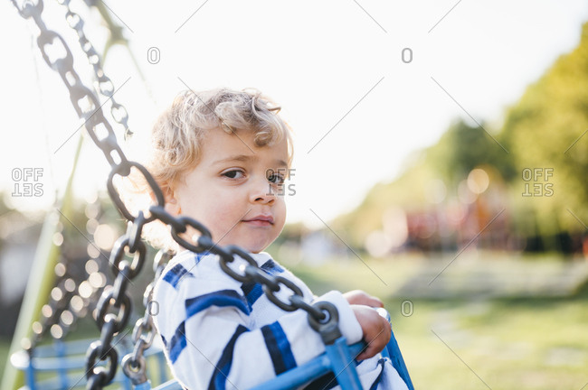Young boy swinging on playground.