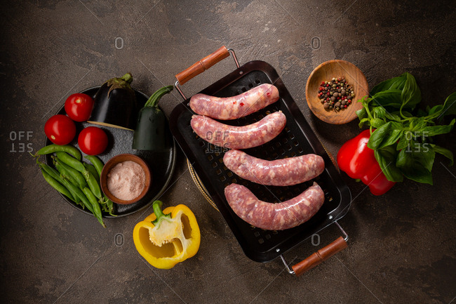 Raw sausages in a metal pan with vegetables