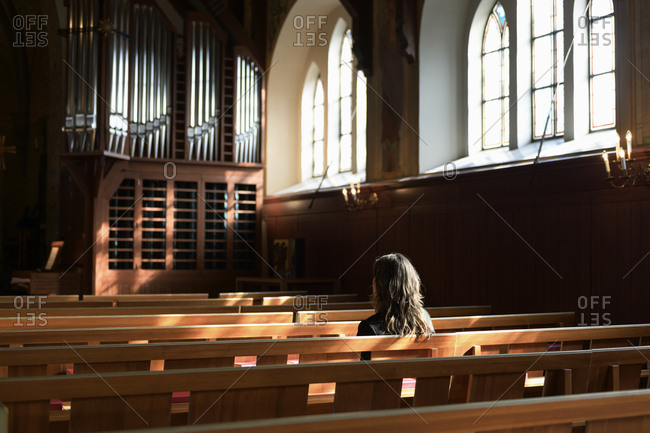 Priest sitting on pew in church