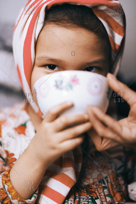 Portrait of a playful girl wearing striped headband and drinking from the cup