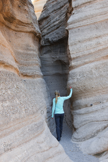 Woman walking into a sandstone slot canyon in Kasha-Katuwe Tent Rocks National Monument, New Mexico
