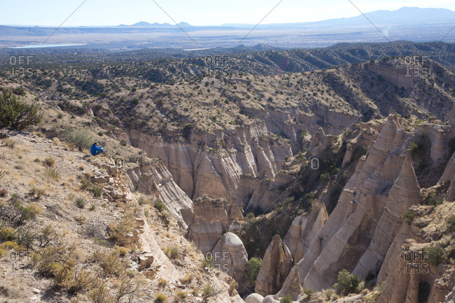 Hiker resting on cliff overlooking Kasha-Katuwe Tent Rocks National Monument, New Mexico