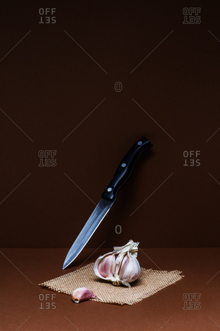 Garlic and knife on brown background