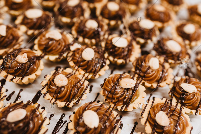 Closeup set of yummy pastry with sweet caramel cream and nuts arranged on parchment paper