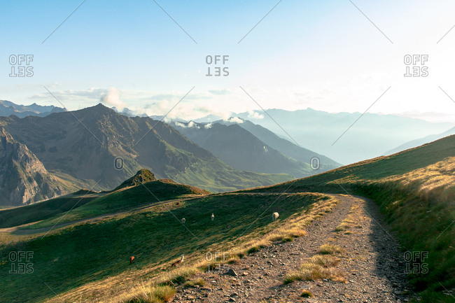 Dirt path extending inland to mossy mountains in foggy mist under cloudy sky