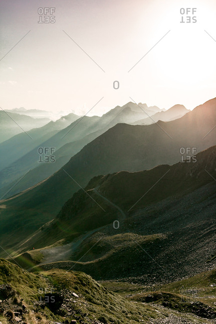 Foggy landscape of amazing mountains in sun light and path between in bright day