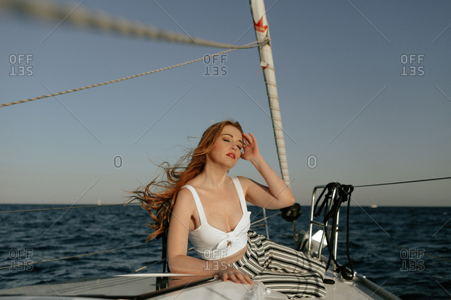 Appealing and attractive redhead lady with closed eyes enjoying while traveling on ship