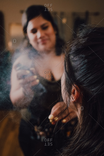 Professional cosmetics worker using fixing spray for customers make up in salon