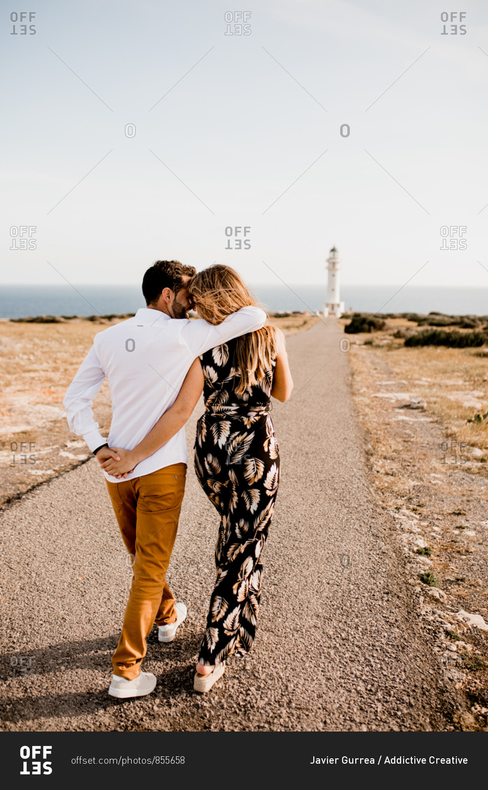 Smiling lovers cuddling on path to sea