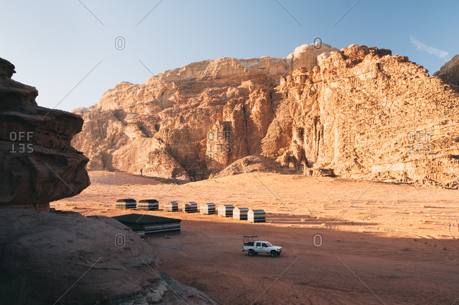 Modern vehicle parked near camp tents during trip through  wadi rum desert on sunny day in jordan