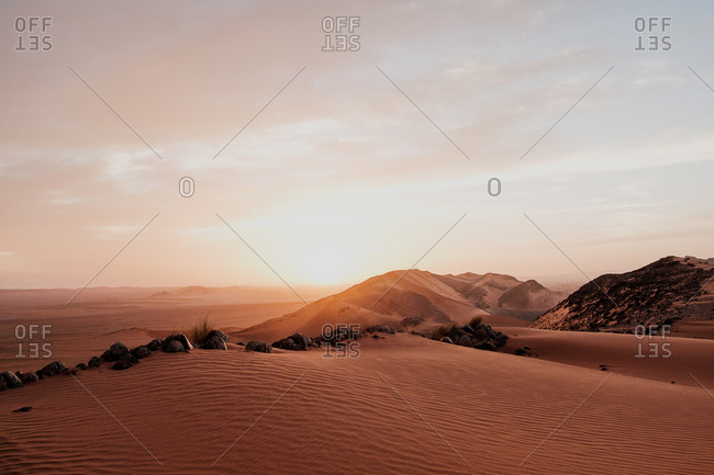Cloudy sundown sky over hills and rocks in arid desert in evening in morocco