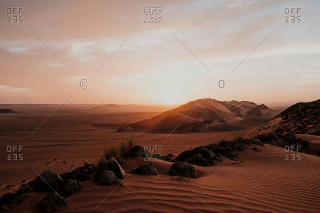 Cloudy sundown sky over hills and rocks in arid desert in evening in morocco