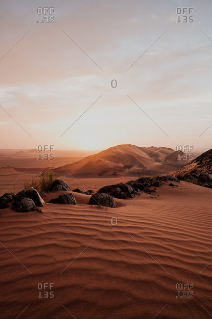 Cloudy sundown sky over hills and rocks in arid desert in evening in morocco