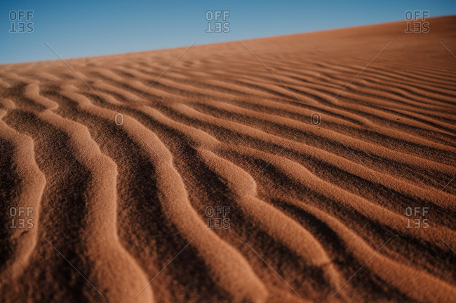Closeup rippled sand surface on dune in arid desert against cloudless blue sky in morocco