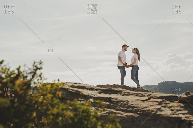 Loving couple holding hands while standing at mountain cliff