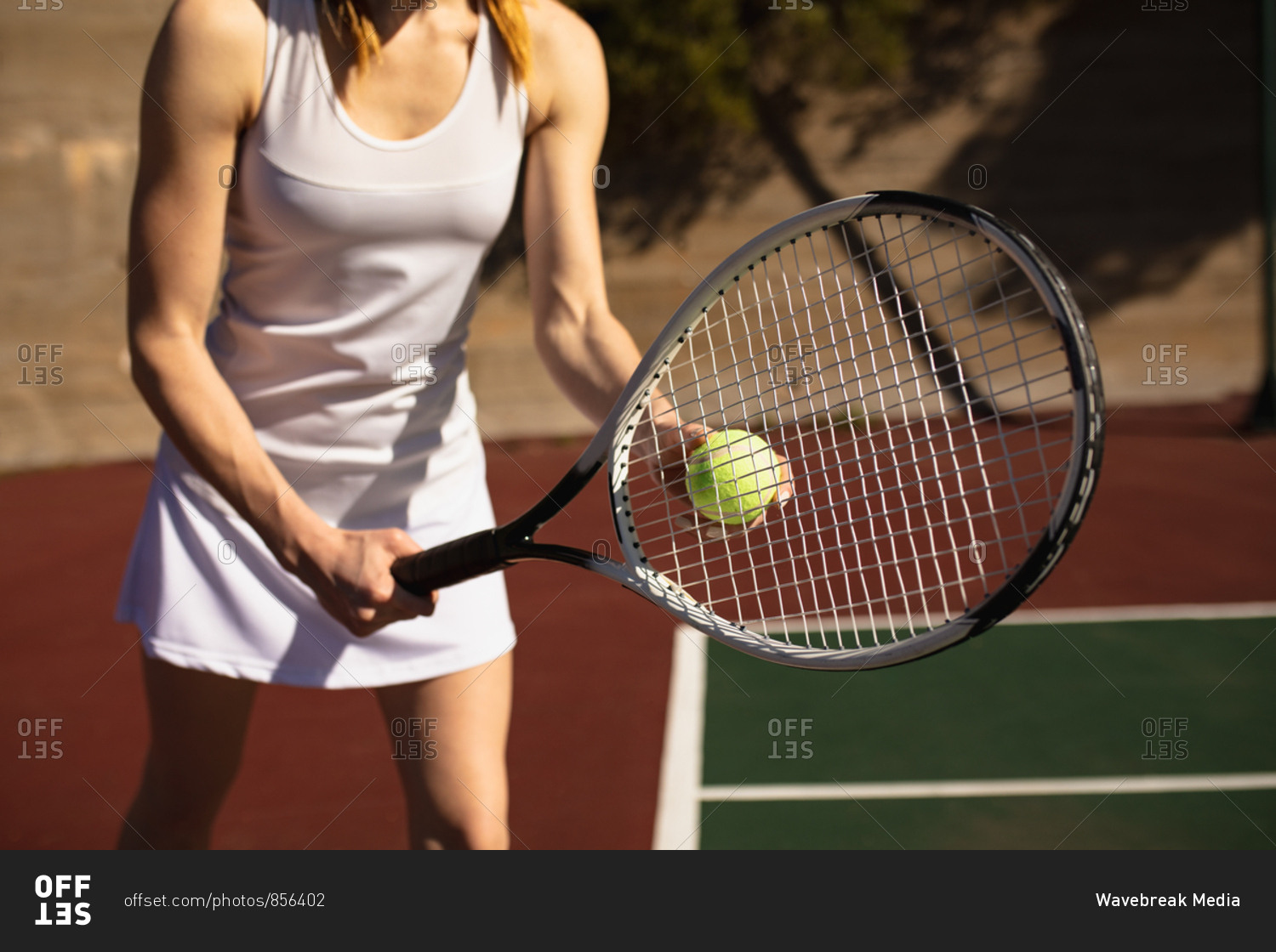 Front view close up of a young Caucasian woman playing tennis on a sunny day, preparing to serve